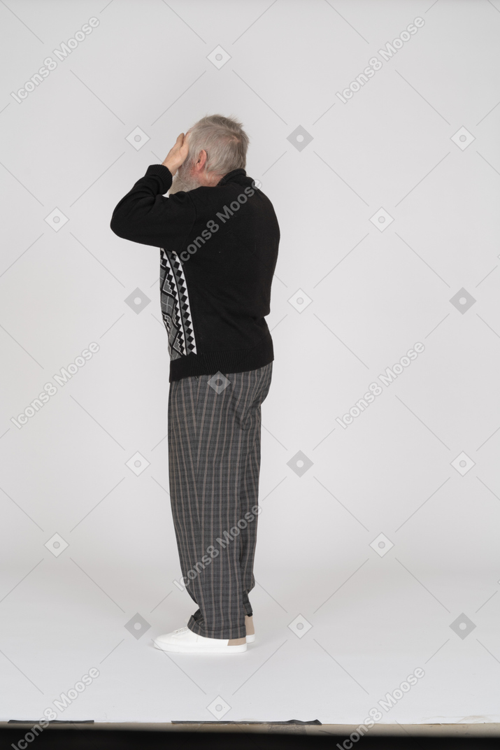 Side view of old man with hands on eyes