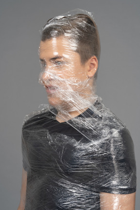 Close up of a young man wrapped in plastic