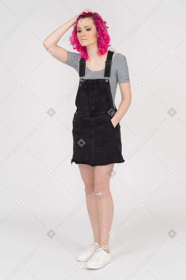 Menina caucasiana pensativa segurando seu cabelo cacheado rosa