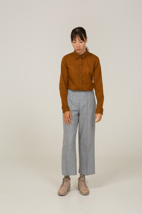 Vista frontal de una joven mujer asiática en calzones y blusa mirando hacia abajo