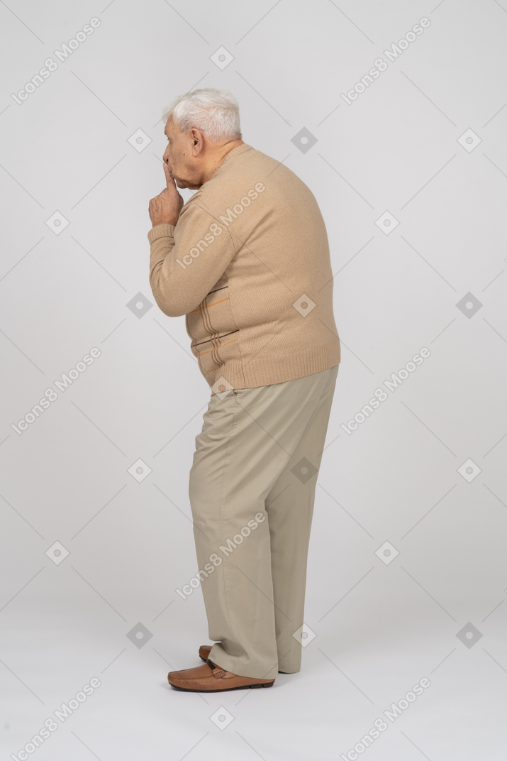 Vista lateral de um velho em roupas casuais, mostrando o gesto shhh