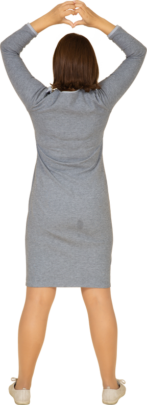 心臓のジェスチャーを示す灰色のドレスを着た女性の背面図