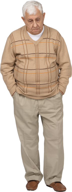 Vue de face d'un vieil homme triste en vêtements décontractés debout avec les mains dans les poches