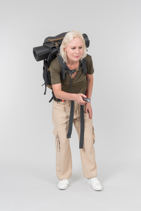 Carrying backpack mature female tourist using dictaphone