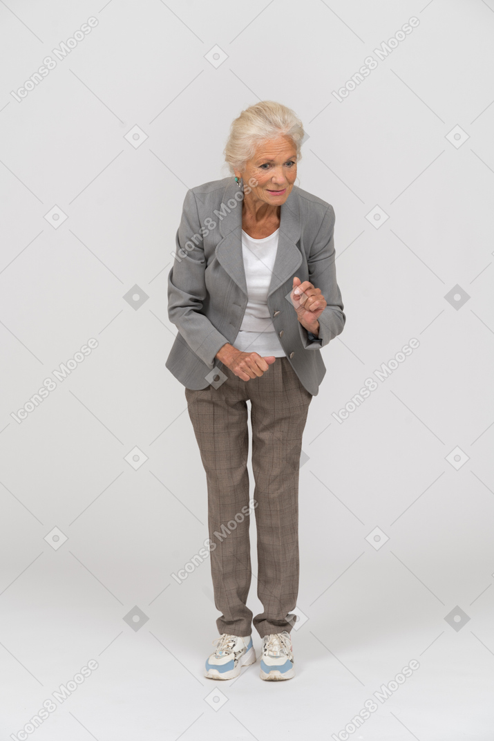 一位身着西装的老太太弯腰解释某事的前视图