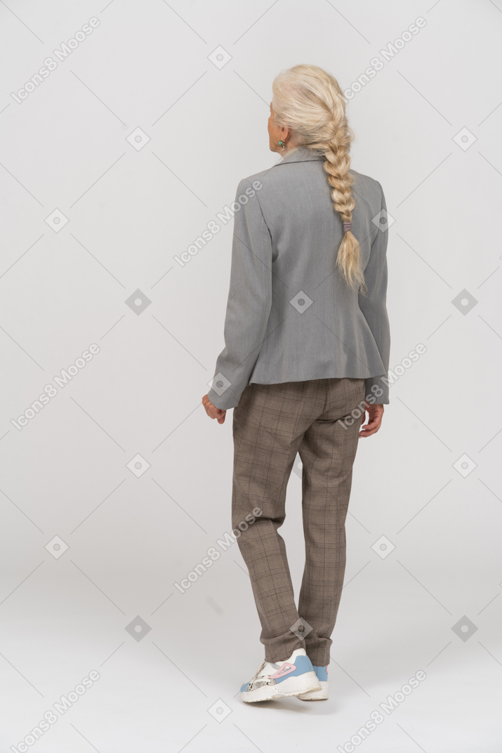 Back view of an old lady in suit posing on one leg