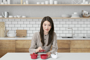 A woman sitting at a table with two red pots