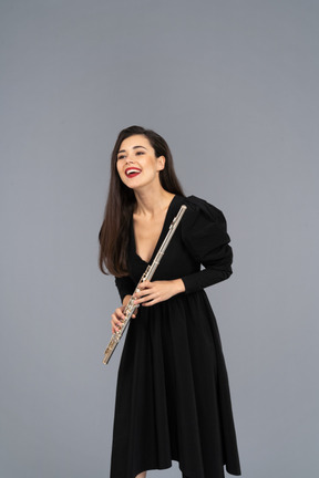 Vista frontale di una giovane donna sorridente in abito nero tenendo il flauto