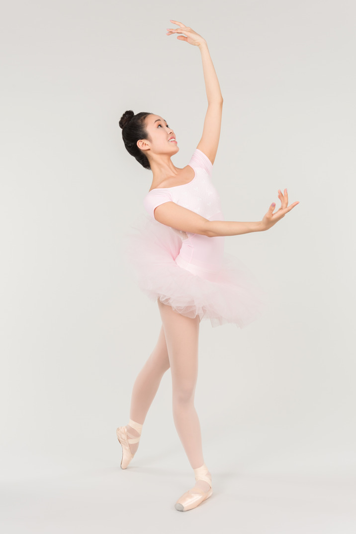 Young asian ballerina standing in ballet position with hands up