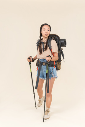 Mulher jovem alpinista andando usando postes de trekking