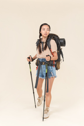 Joven excursionista mujer caminando con bastones de trekking