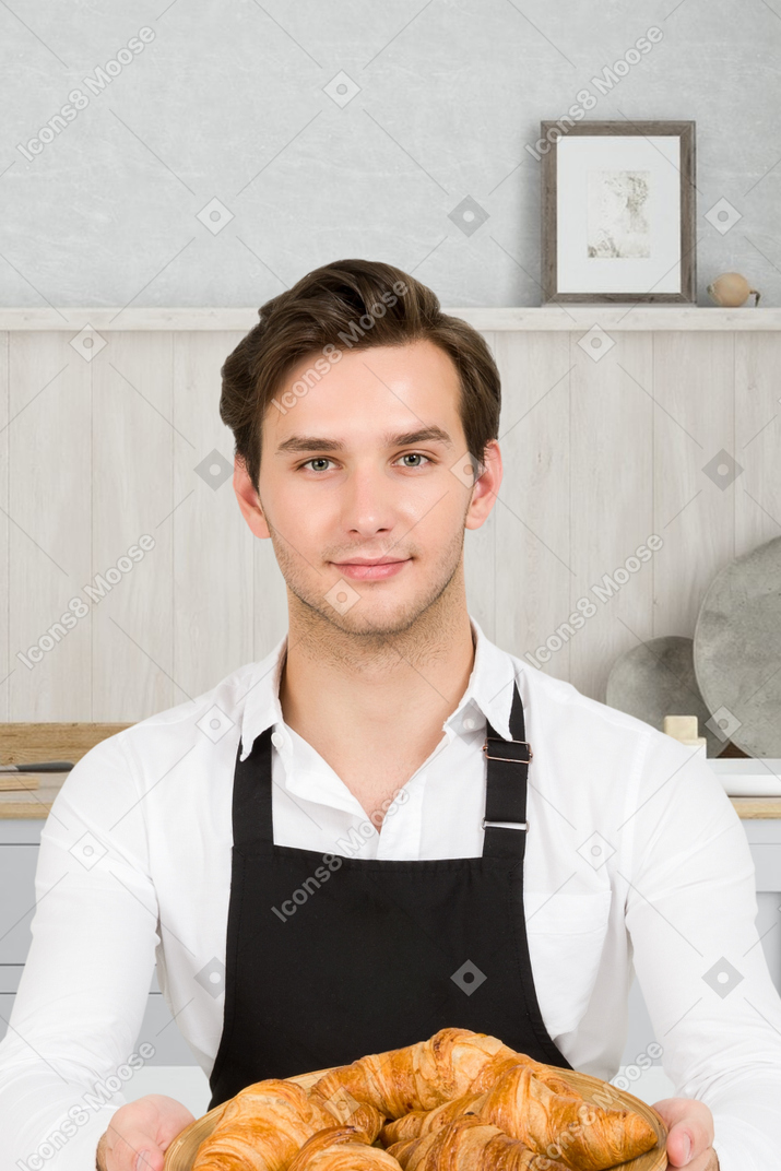 Young man holding freshly baked croissants