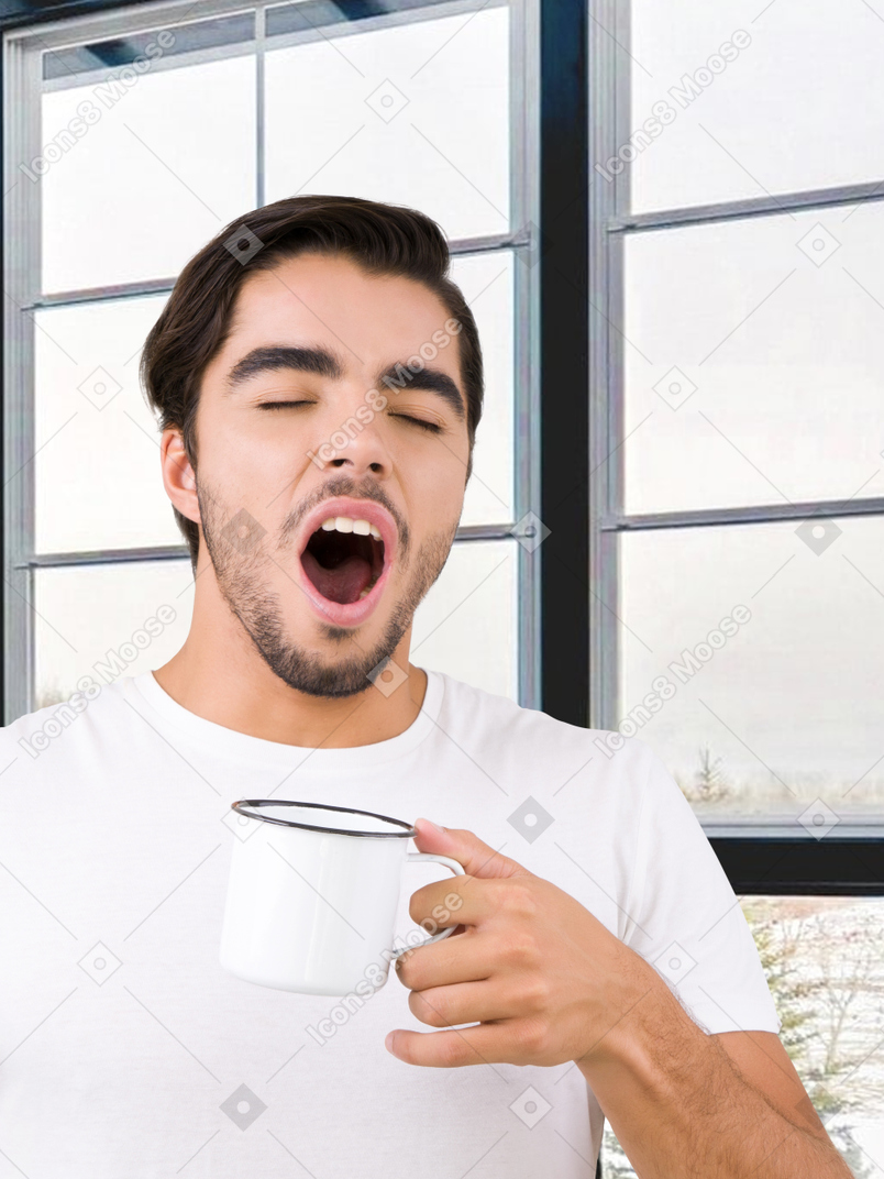 Homem segurando uma xícara e bocejando