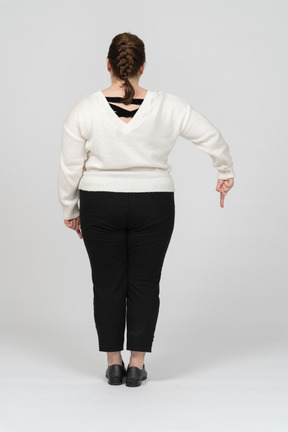Plus size woman in white sweater pointing with a finger