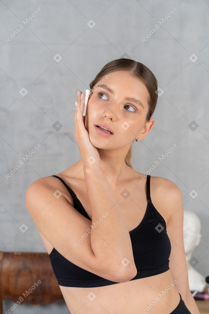 Woman wiping her face with a cotton pad