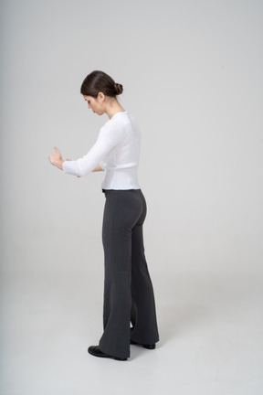 Young woman in black pants and white blouse standing in profile