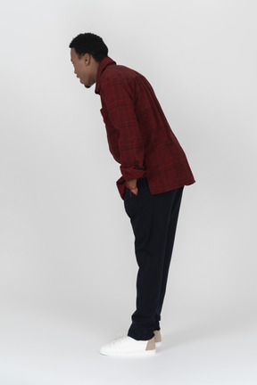 Side view of young man bending down and looking at something