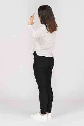 Three-quarter back view of a greeting young indian female in casual clothing