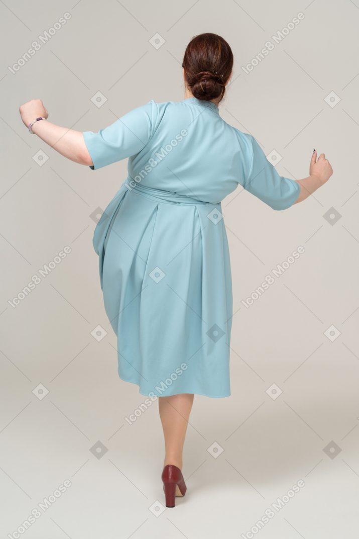 穿着蓝色裙子走路的 s 女人的后视图
