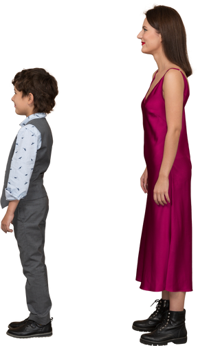 Stylsih woman in red dress and boy in suit vest standing in profile