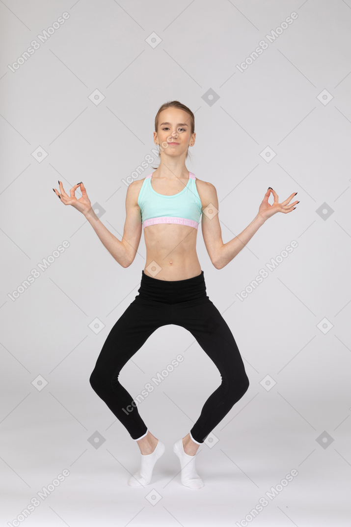 Front view of a teen girl in sportswear putting legs wide apart