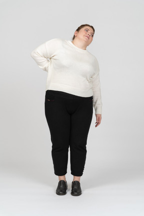 Mulher plus size com roupas casuais, sofrendo de dores na parte inferior das costas