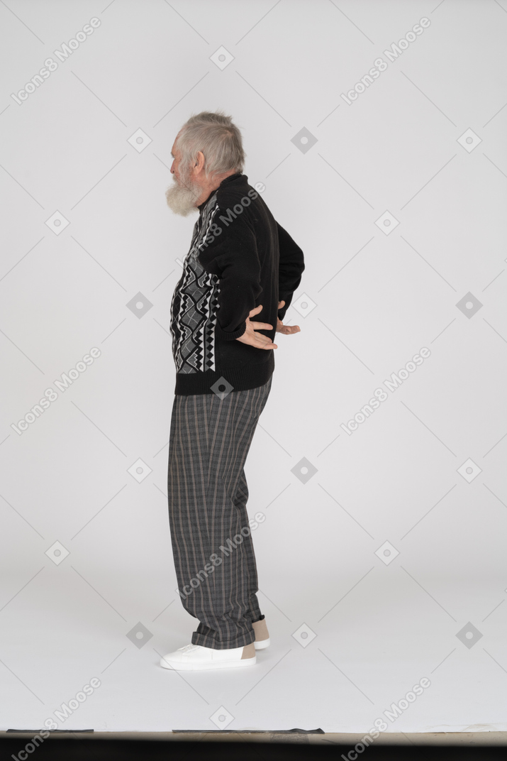 Side view of old man with hands behind back