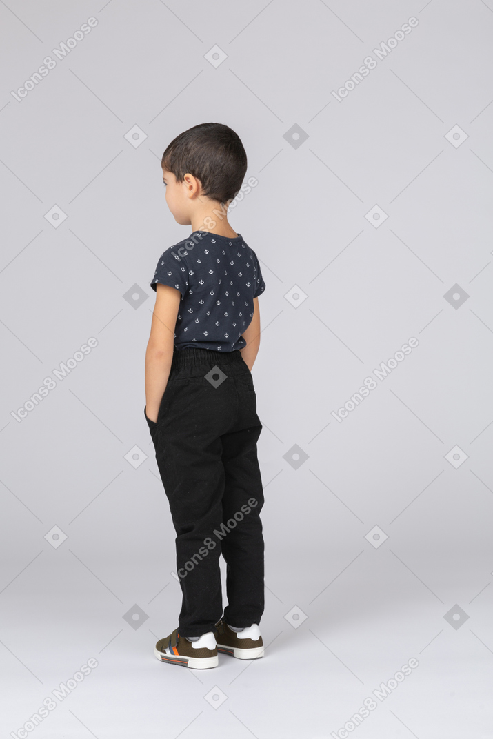 一个穿着休闲服、双手插在口袋里的可爱男孩的后视图