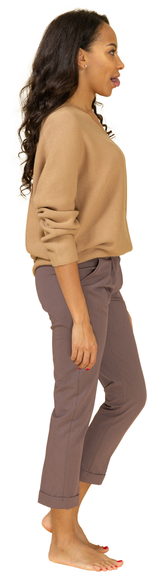 Vista laterale di una giovane donna in abiti casual che mostra la lingua