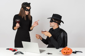 Female worker in cat costume talking to male colleague dressed like a zorro