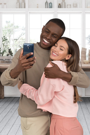 A man hugging a woman while holding a cell phone