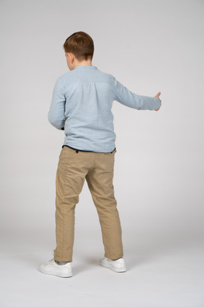 Young boy shirt and pants extending his right arm