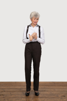 Front view of a crying old lady in office clothing holding hands together