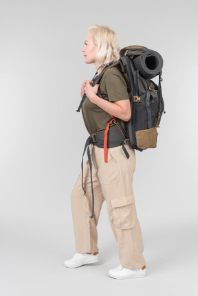 Mature female tourist standing in profile and carrying heavy backpack