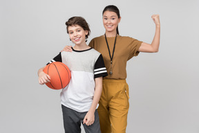 Pe female teacher showing bicep standing next to her pupil