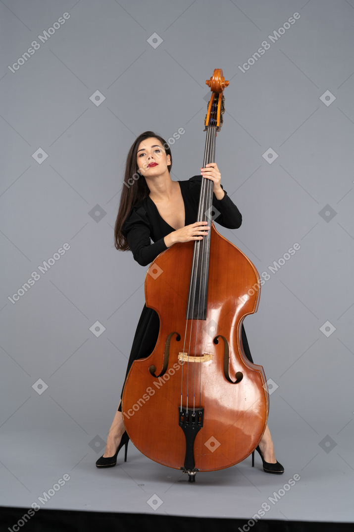 Vista frontale di una giovane donna in abito nero che suona il suo contrabbasso