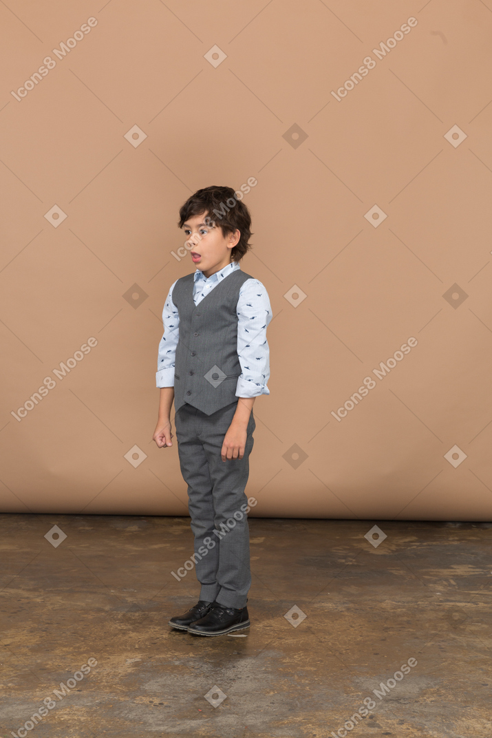 Vista frontale di un ragazzo impressionato in abito grigio