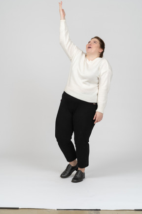 Vista frontal de uma mulher impressionada com roupas casuais apontando para cima com uma mão