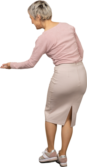 歓迎のジェスチャーをしているカジュアルな服装の女性の背面図