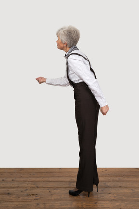 Side view of an angry old lady in office clothing outstretching her hand