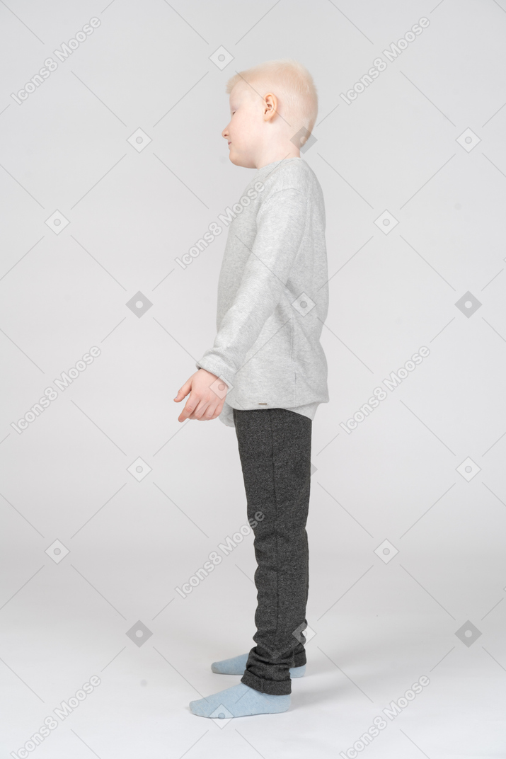 Vista lateral de um menino de pé com a mão afastada