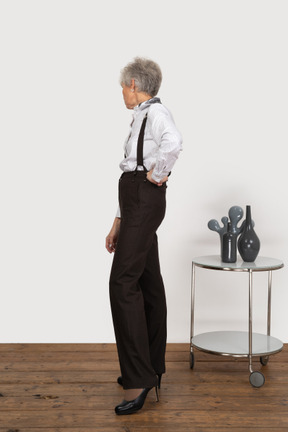 Seitenansicht einer neugierigen alten dame in der bürokleidung, die beiseite schaut