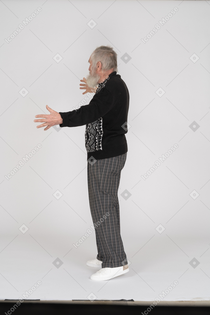 Side view of old man showing long gesture with hands