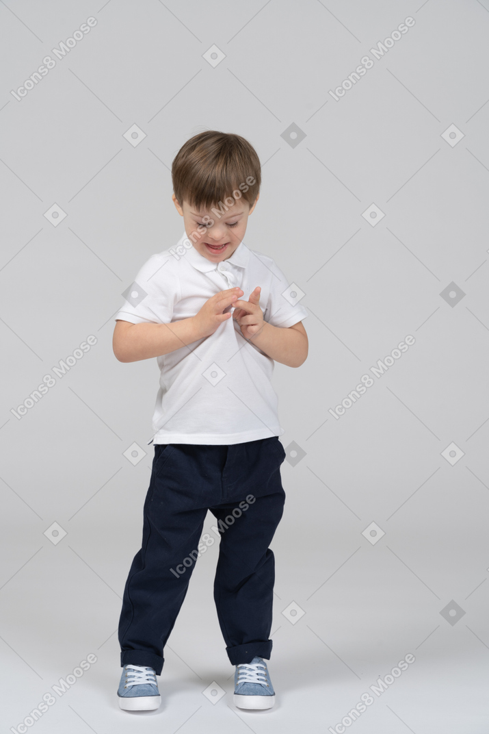 Front view of little boy tugging on his t-shirt