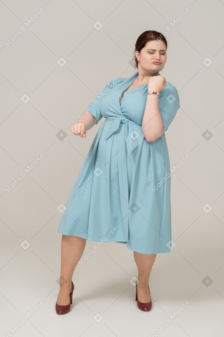 Vista frontal de uma mulher de vestido azul fingindo que está tocando violino