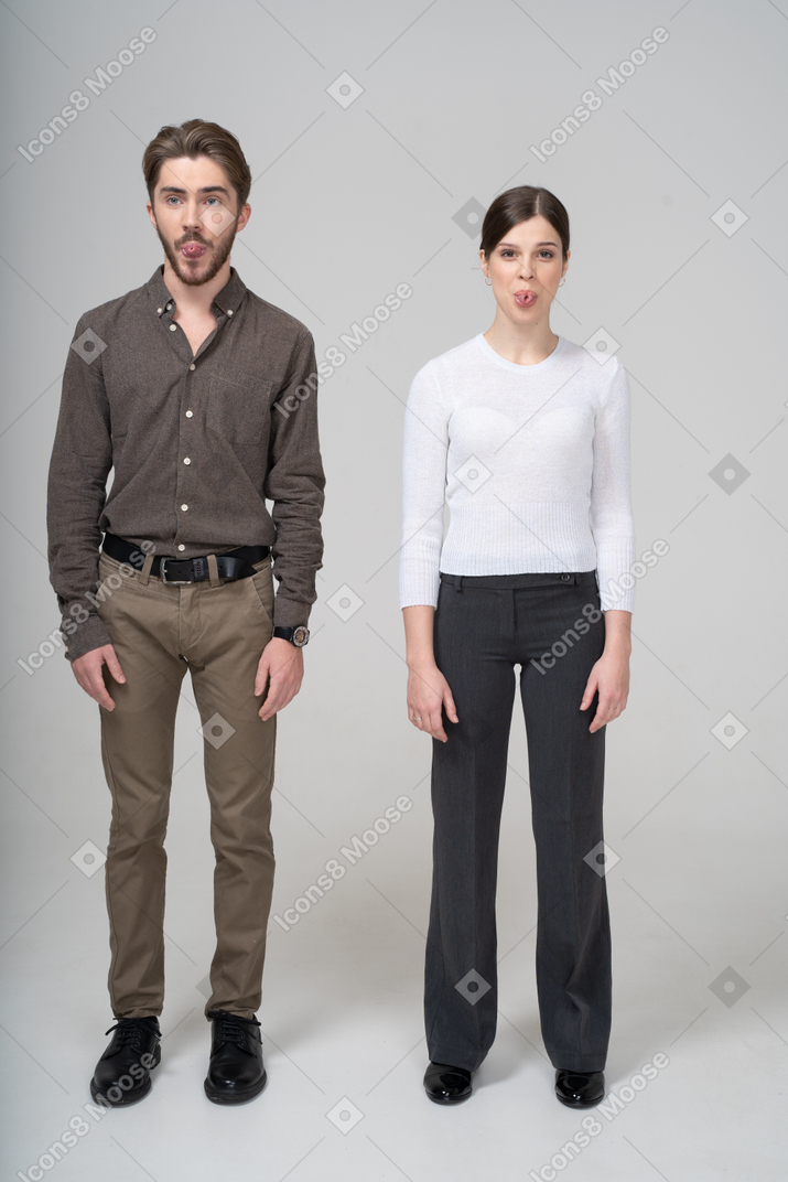舌を示すオフィス服の若いカップルの正面図