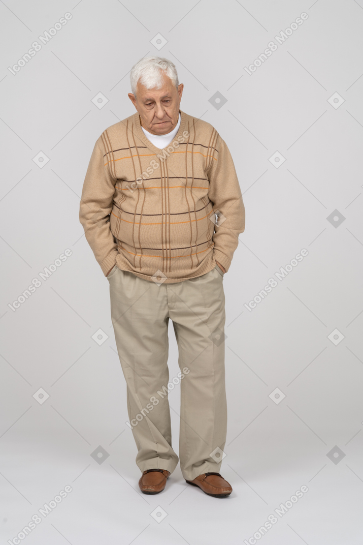 ポケットに手を入れて立っているカジュアルな服を着た悲しい老人の正面図