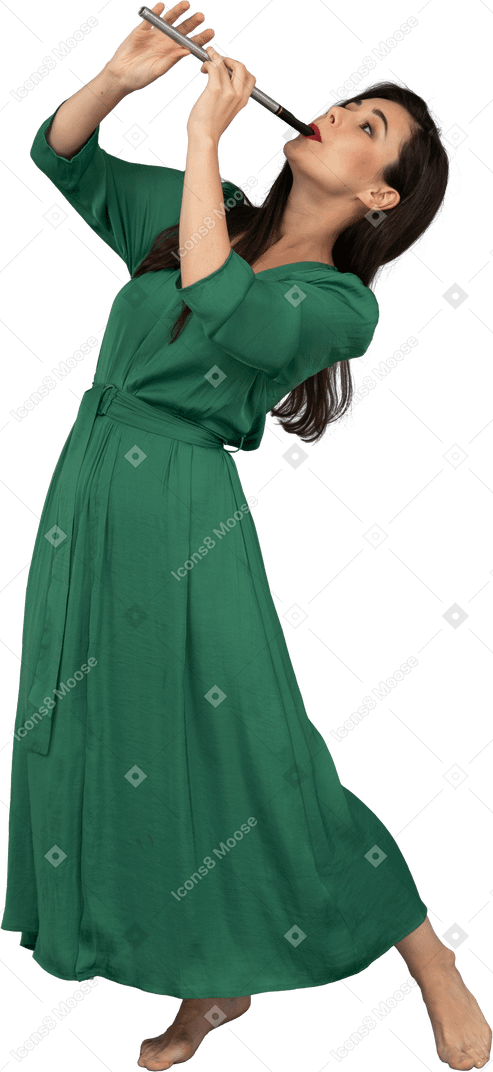 後ろに寄りかかってフルートを演奏する緑のドレスを着た若い女性の4分の3のビュー