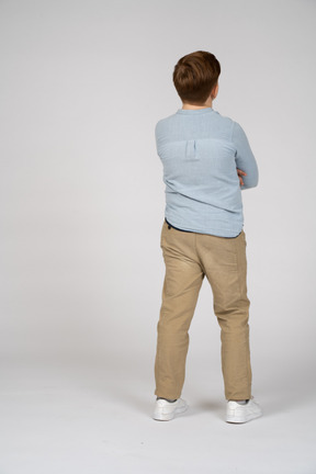 Vista trasera de un niño posando con los brazos cruzados