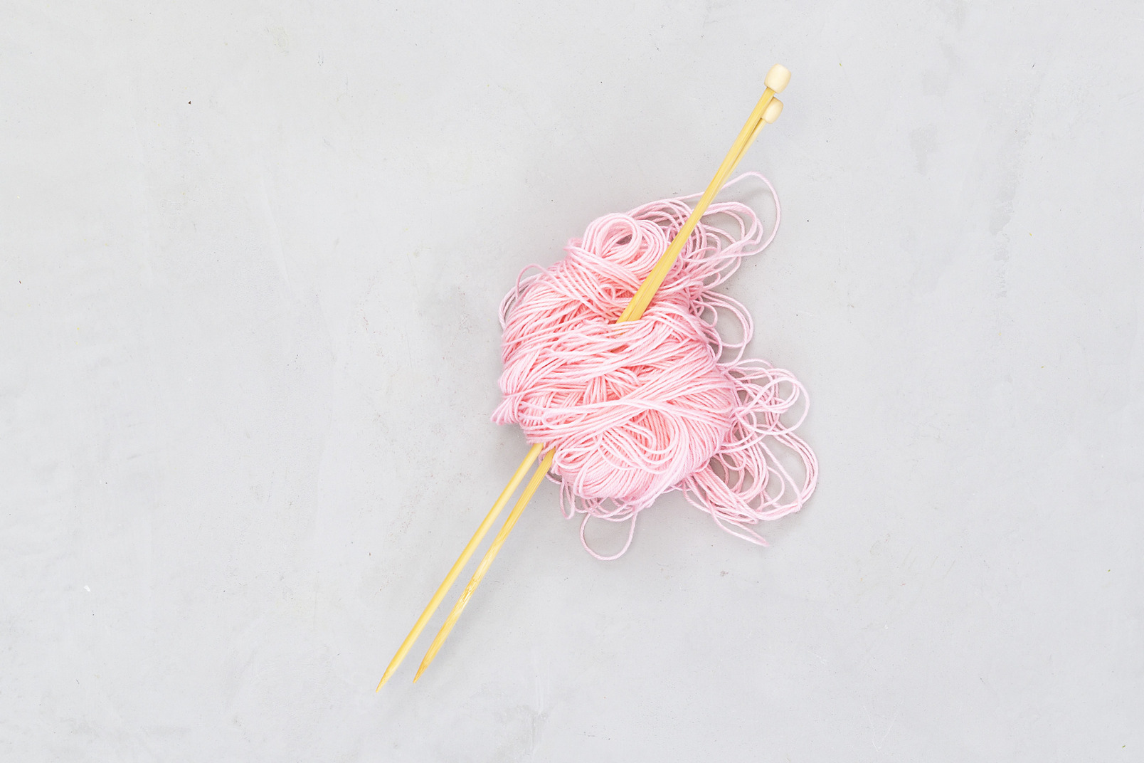 Pink yarn with wooden needles in it